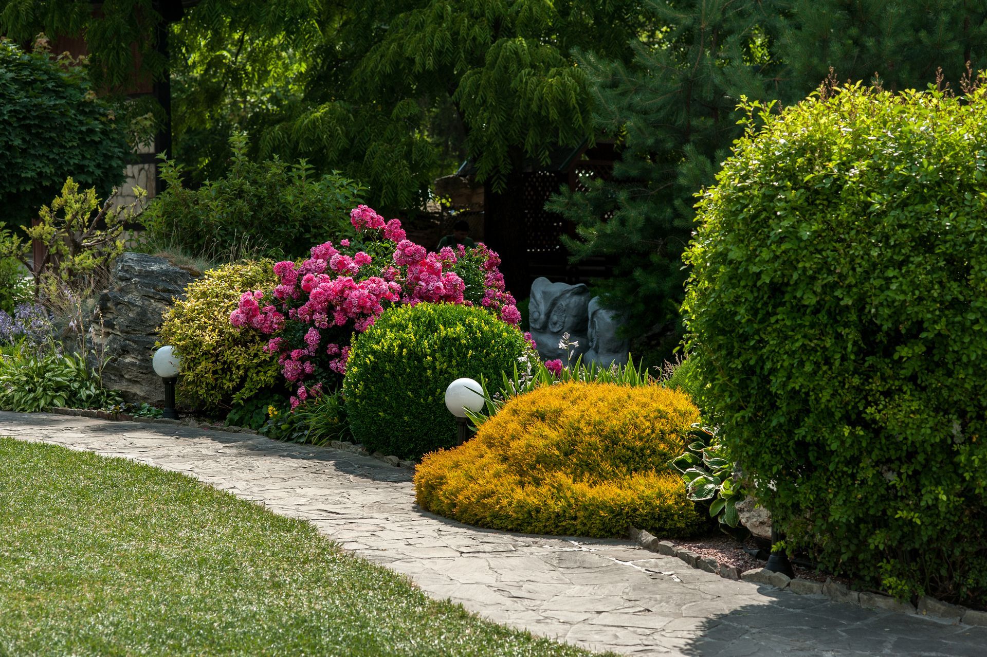 Beautiful landscape design with various bushes, conifers, and colorful flowers.