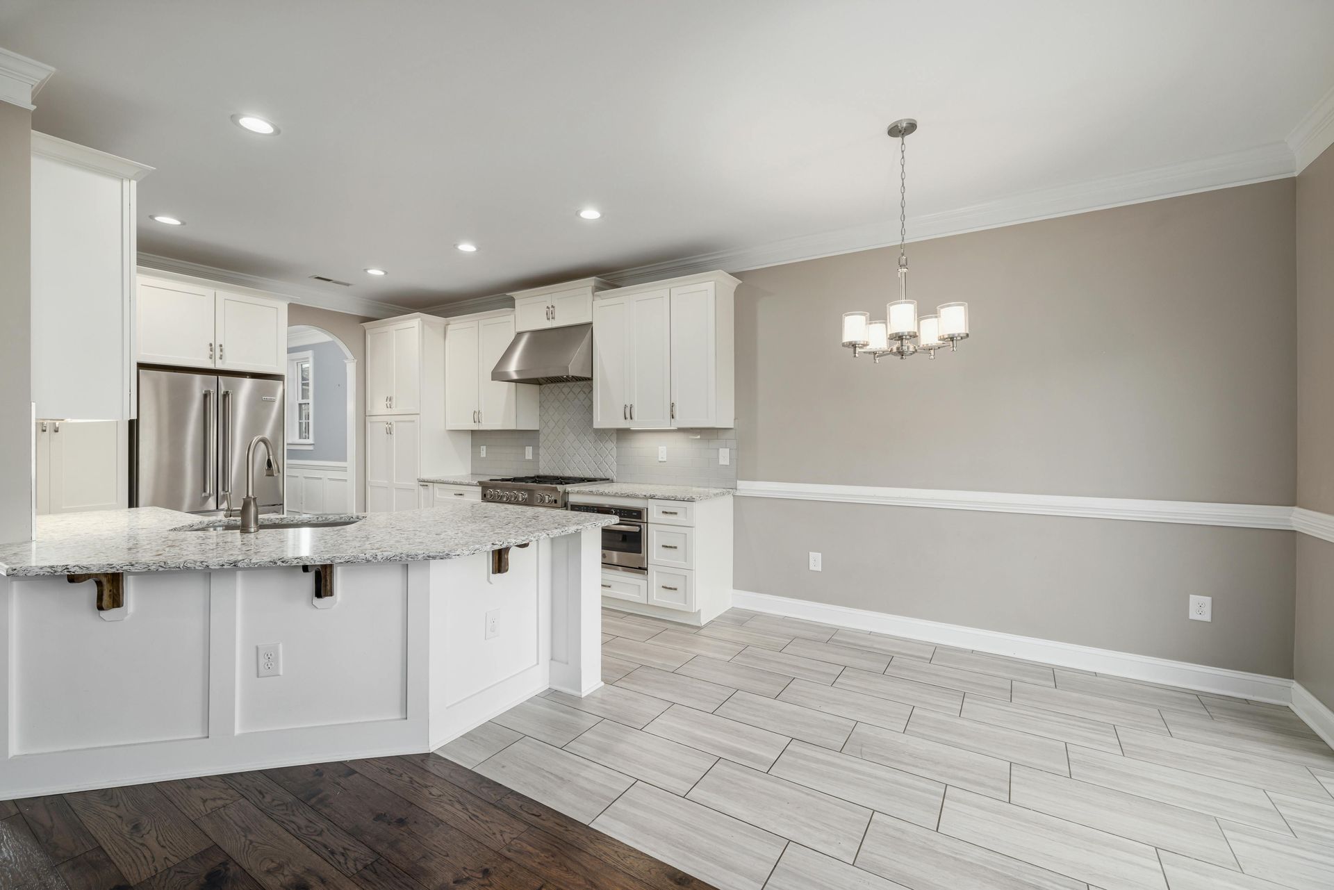 An empty kitchen with white cabinets and granite counter tops.