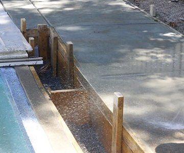 A concrete walkway is being built next to a pool.