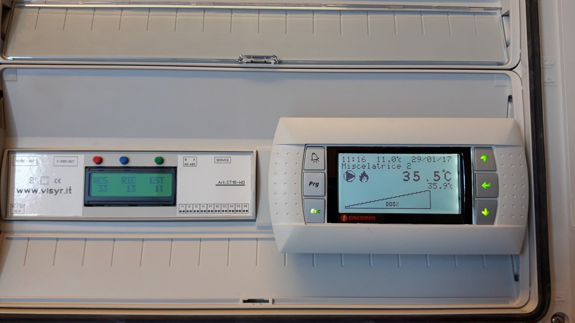 Un quadro elettrico a parete dotato di due unità di controllo digitali con schermi LCD interattivi e spie luminose.