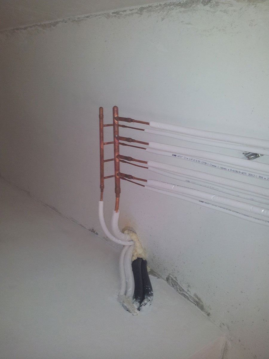 Connettori di cablaggio elettrico in rame a vista, fissati a cavi piatti bianchi montati su una parete interna liscia.