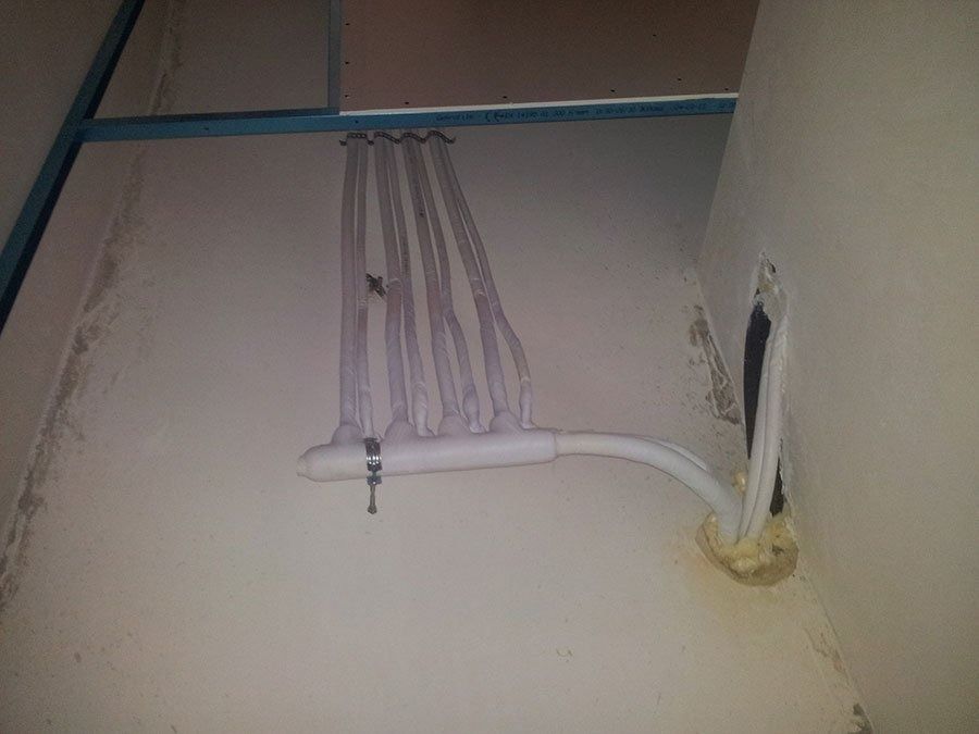 Cavi bianchi organizzati in una struttura a collettore montata a soffitto e a parete, fissati con un morsetto e isolamento in schiuma.