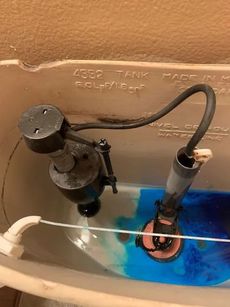 A close up of a toilet tank with blue liquid in it.