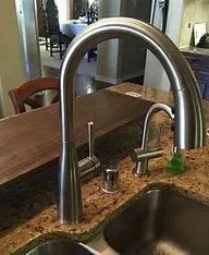 A kitchen sink with a stainless steel faucet on a granite counter top.