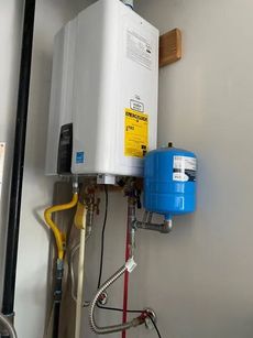 A water heater is hanging on a wall next to a blue tank.