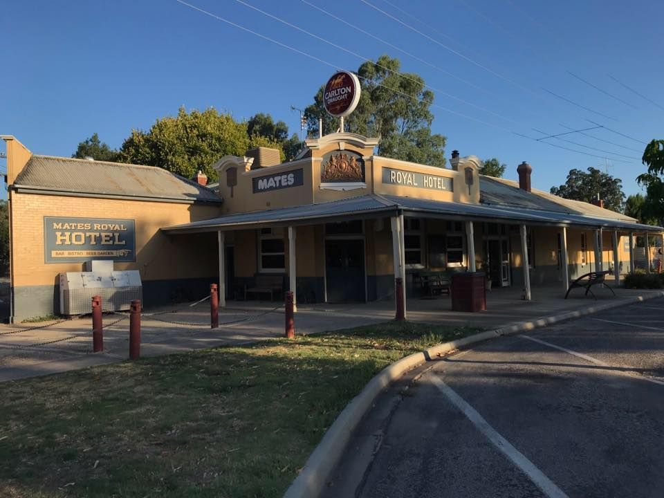 Exterior of the Mate's Hotel, a single-story building with a beige facade and a large neon sign, in a rural setting.