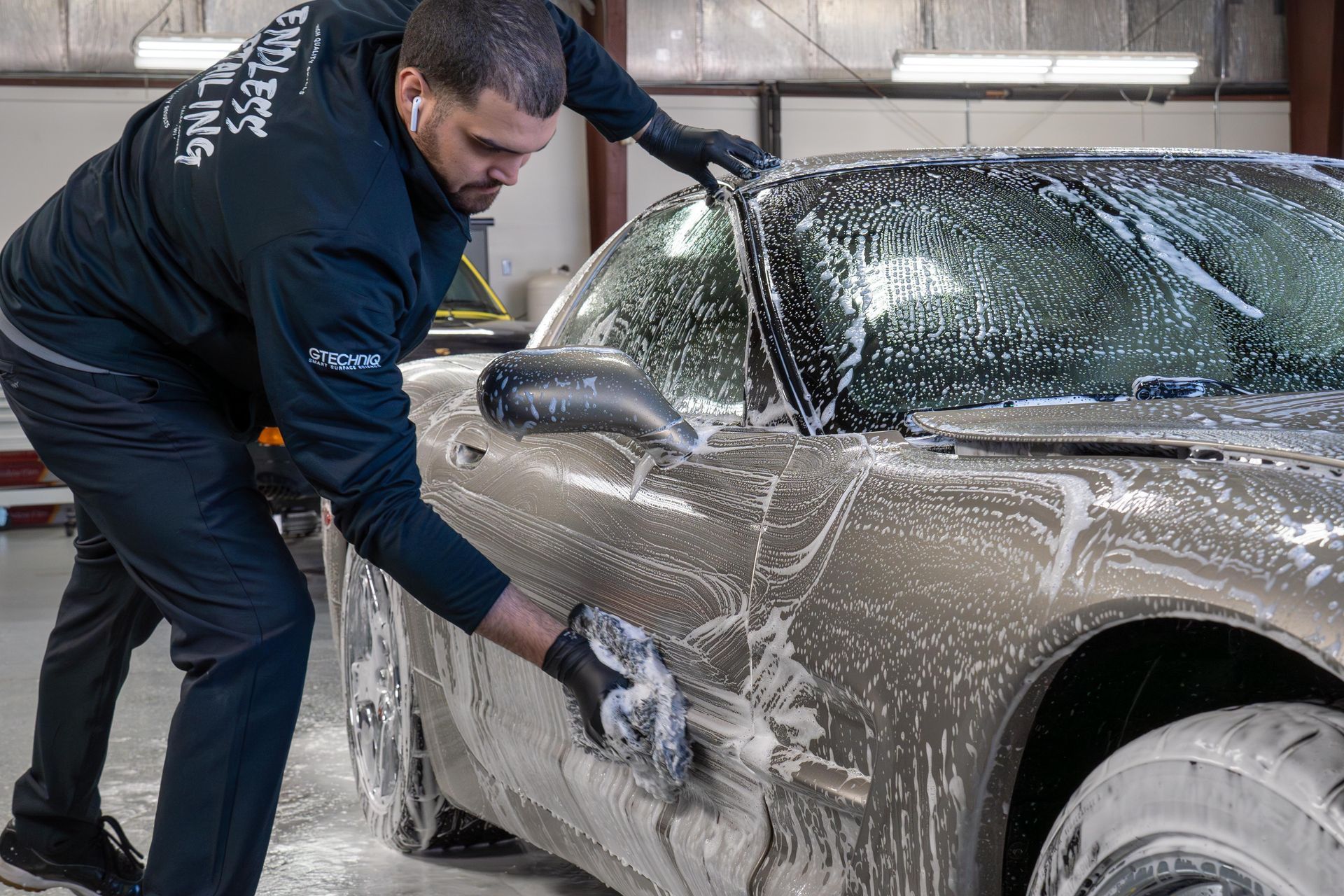 Detailer washing a car, showing car wash practices for vehicles with protective film.