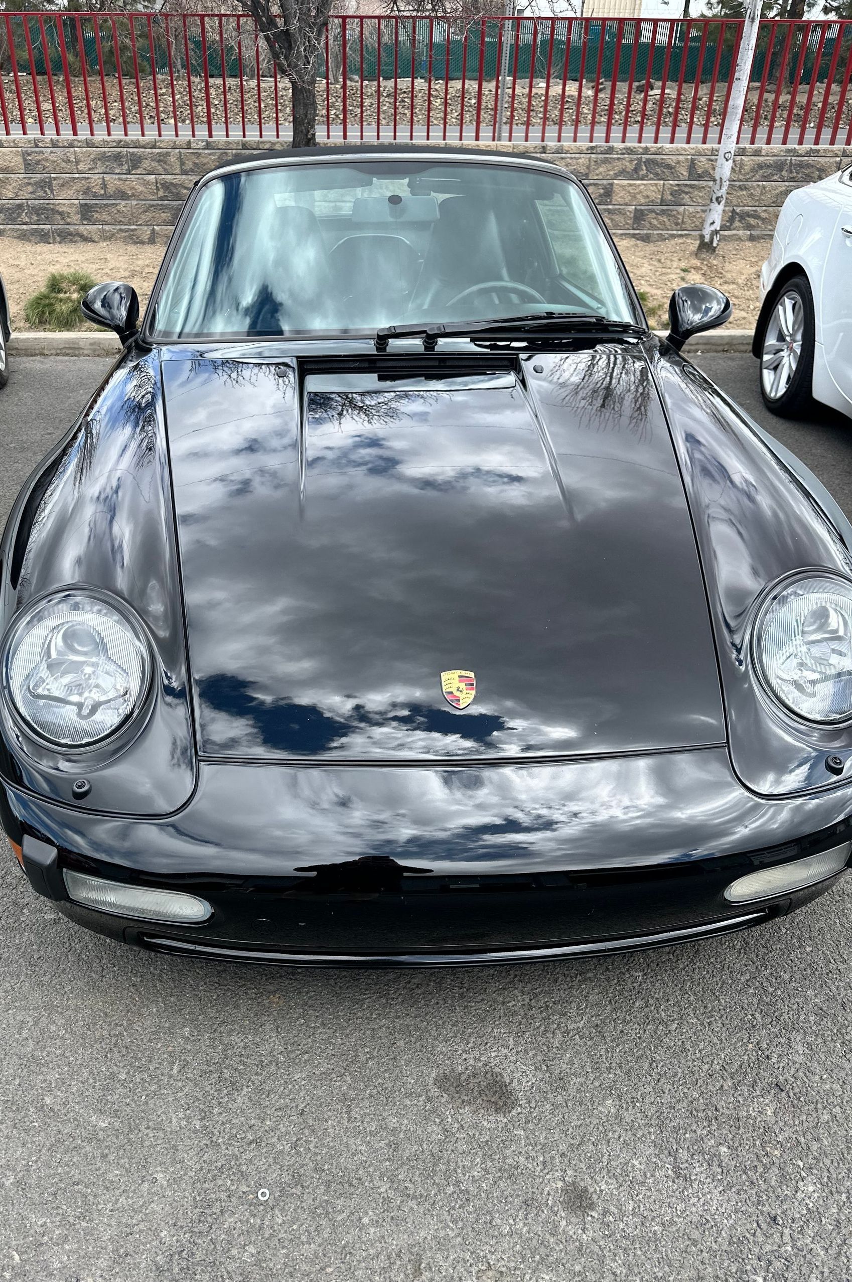 A black porsche 911 is parked in a parking lot.