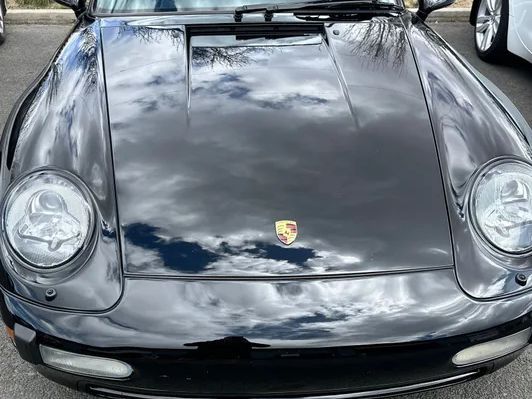 Front view of a black Porsche with reflective shine, indicating a ceramic coating on the surface.