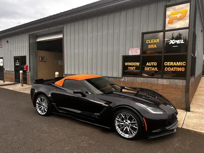 Black Corvette outside a shop with PPF applied, reflecting light. 