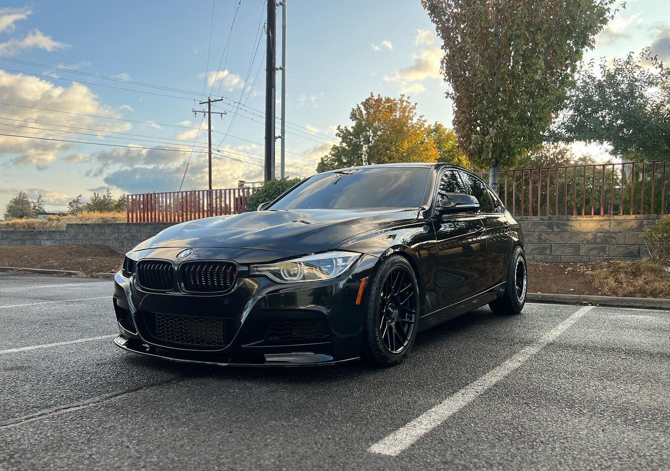 A black bmw m3 is parked in a parking lot.