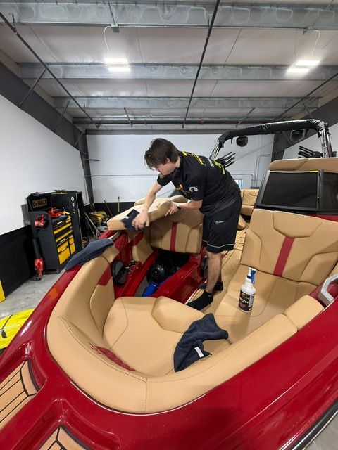 A man is working on a red boat in a garage