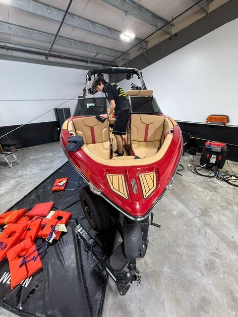 A man is working on a red boat in a garage