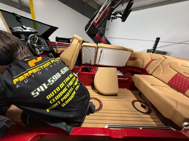 A man is working on a boat with perfection auto glass on his back