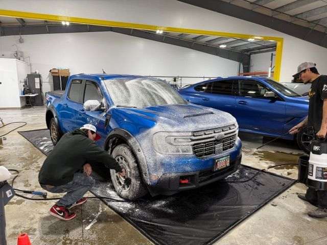 Two men are washing a blue truck in a garage.