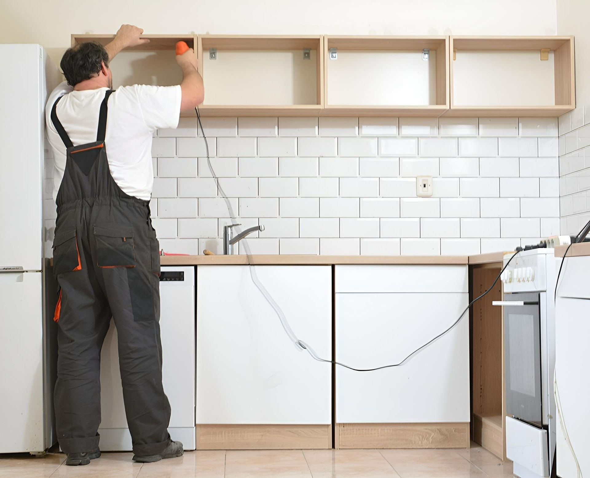 A Man in Overalls is Working in a Kitchen — Precision Kitchens & Cabinets in Lennox Head, NSW