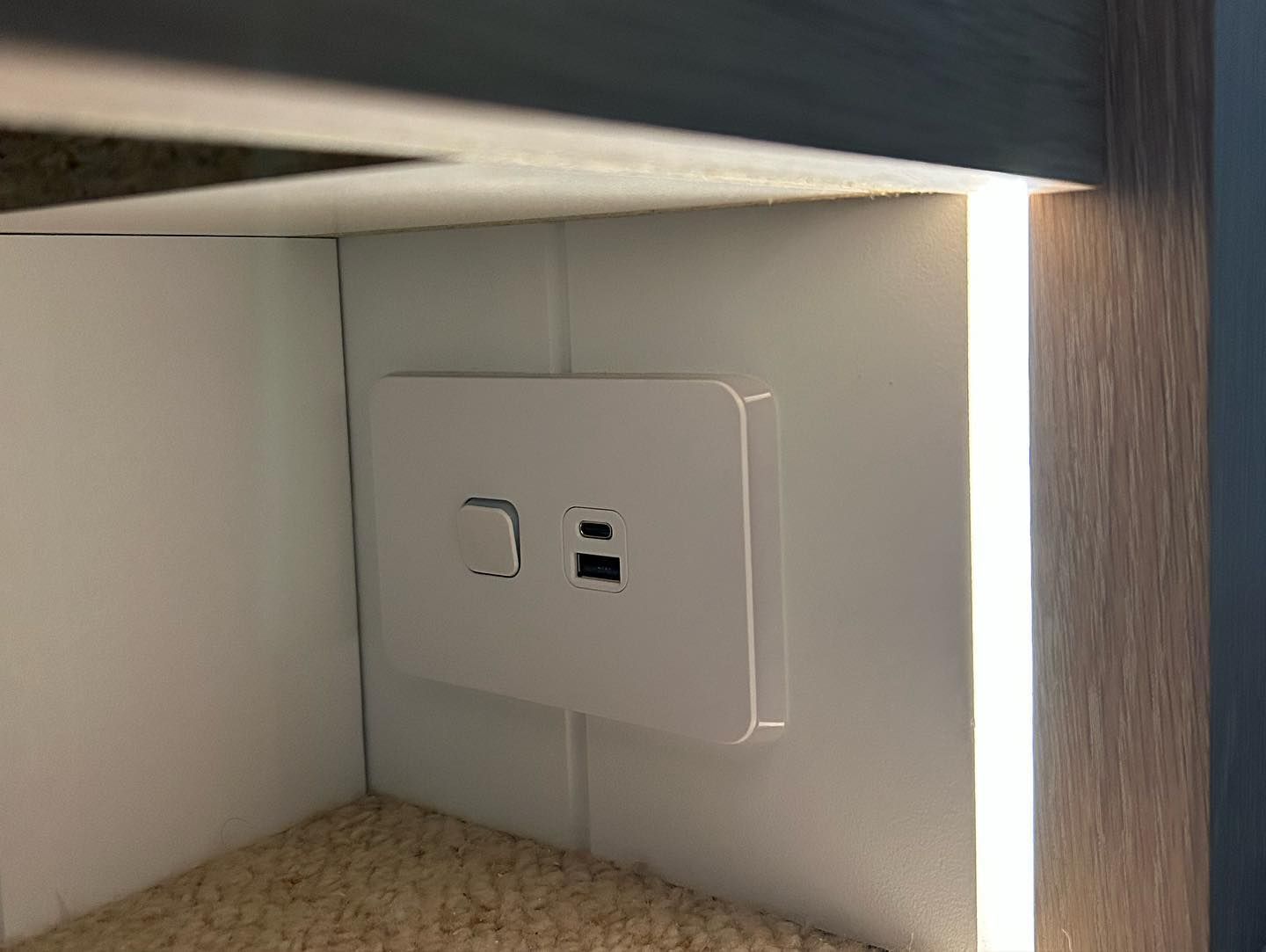A White Electrical Outlet is Sitting Under a Shelf in a Room — Precision Kitchens & Cabinets in Ballina, NSW