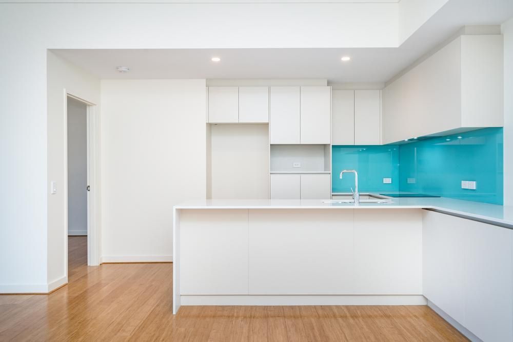 An Empty Kitchen With White Cabinets and Blue Counter Tops — Precision Kitchens & Cabinets in Ballina, NSW