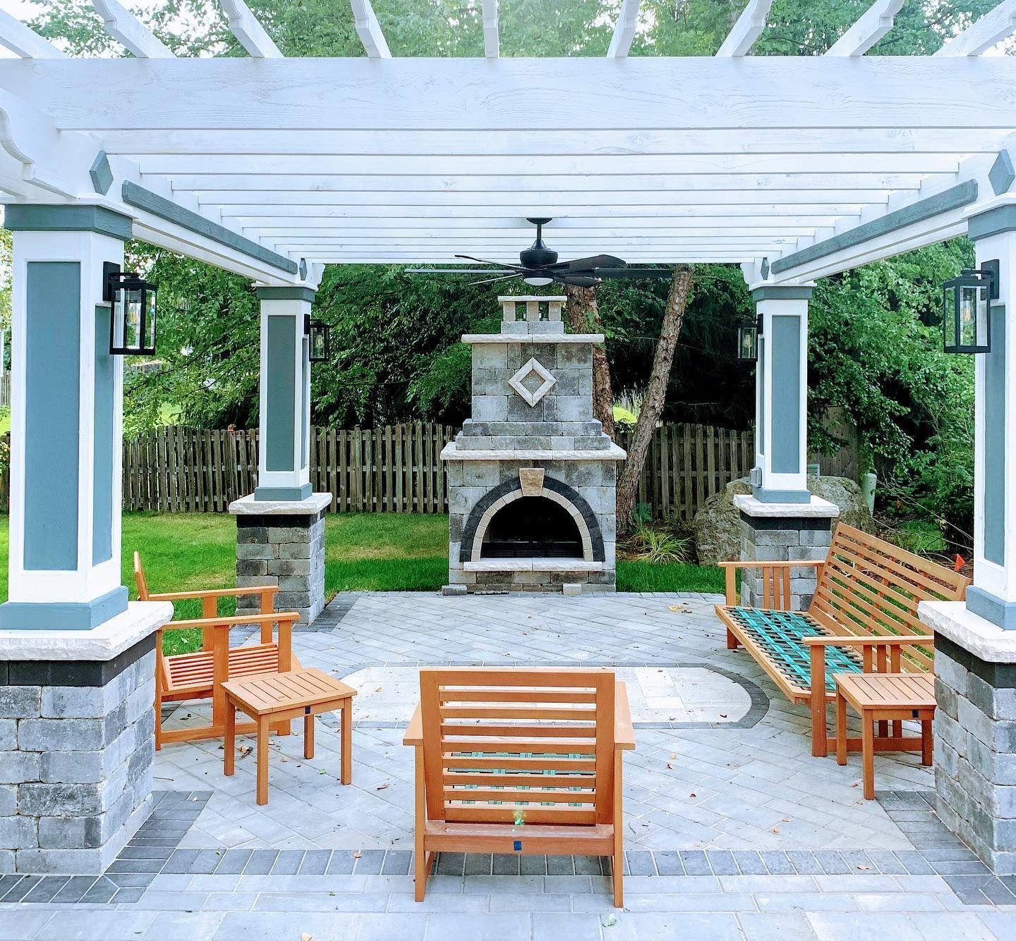 Outdoor patio with pergola, fireplace, and wooden furniture.