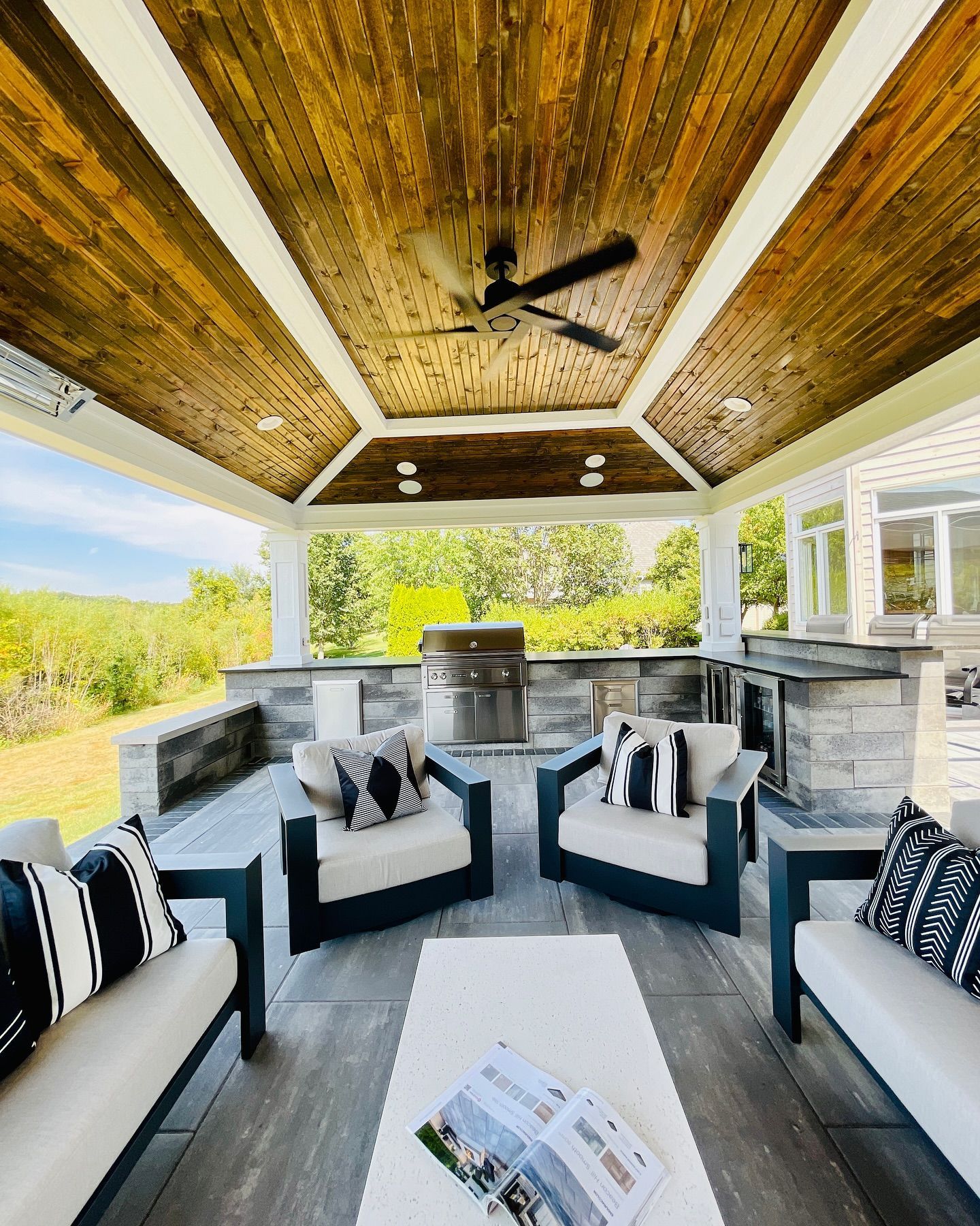 Outdoor patio with seating, grill, and wood-paneled ceiling.