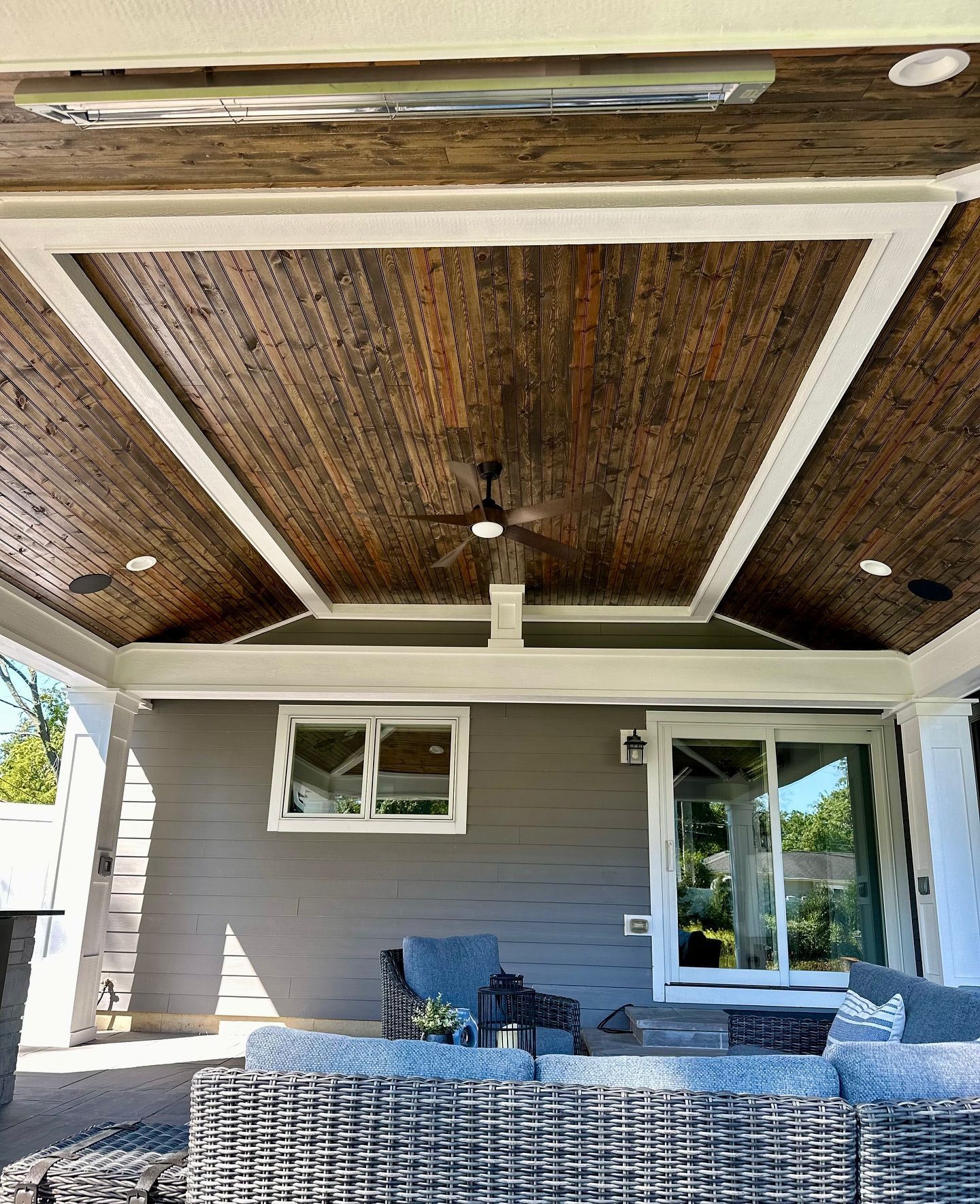 Patio with a dark wood ceiling, white trim, gray siding, and outdoor furniture.