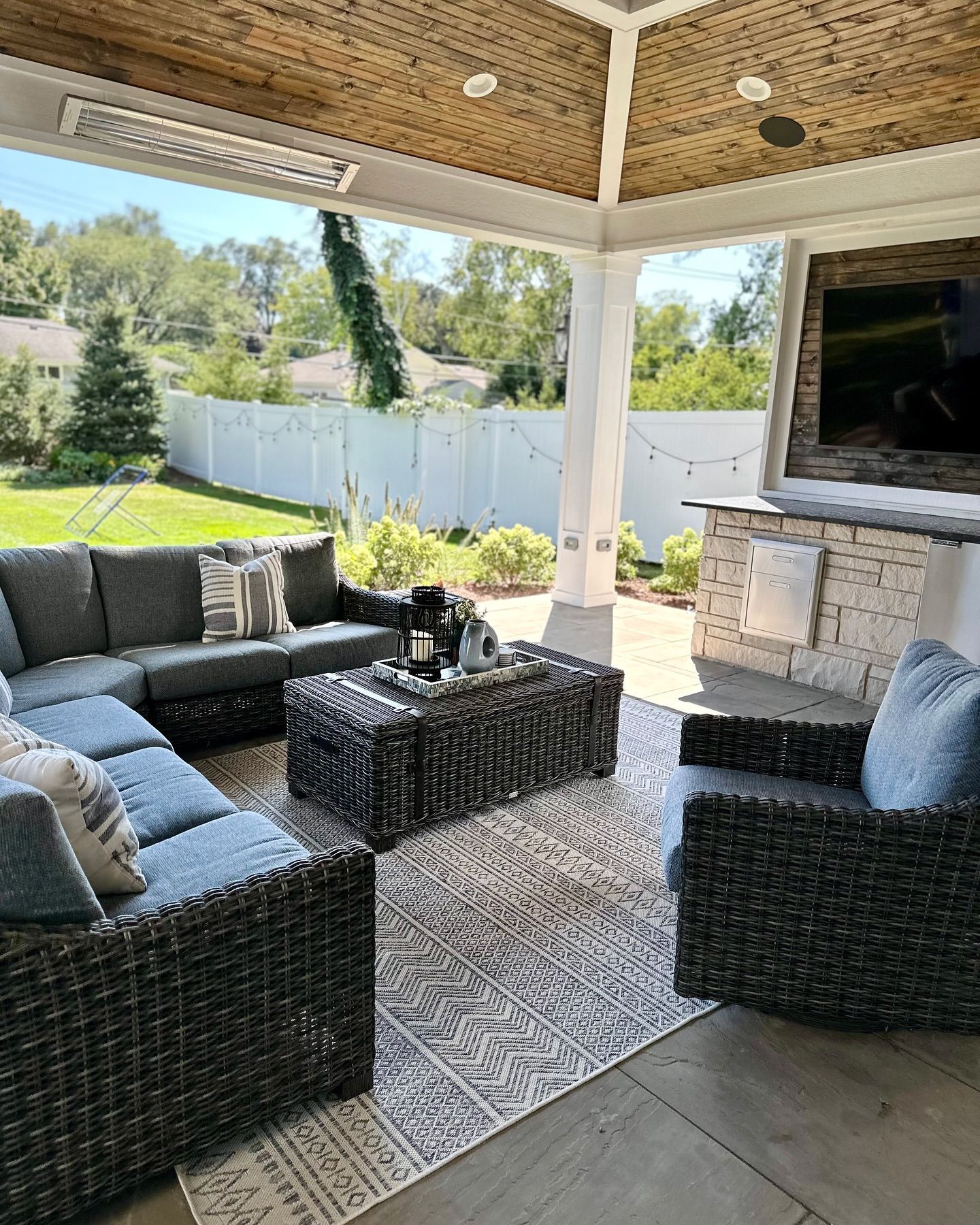 Covered outdoor patio with wicker furniture, a rug, and a television.