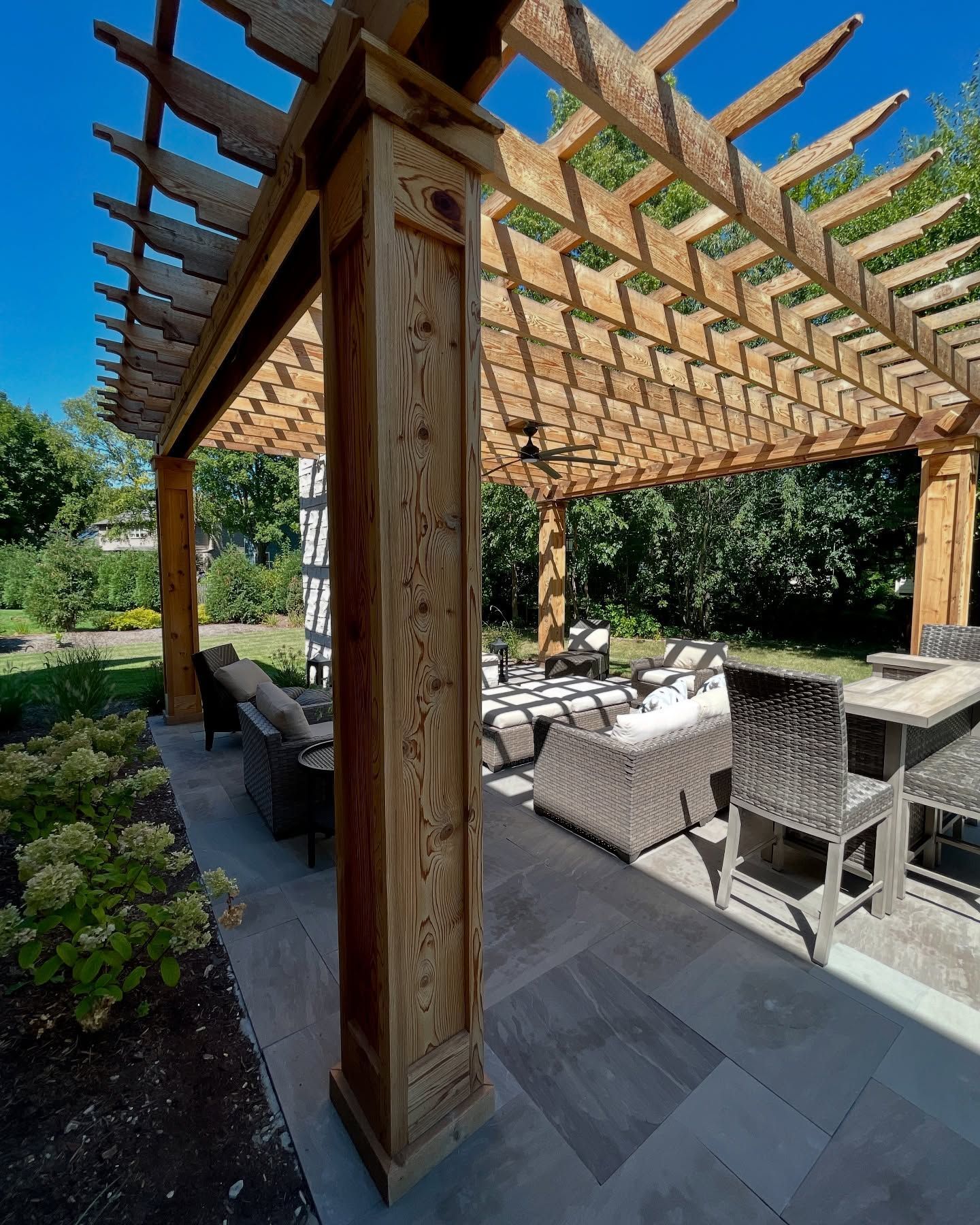 Wooden pergola over a patio with outdoor furniture, sunny day.