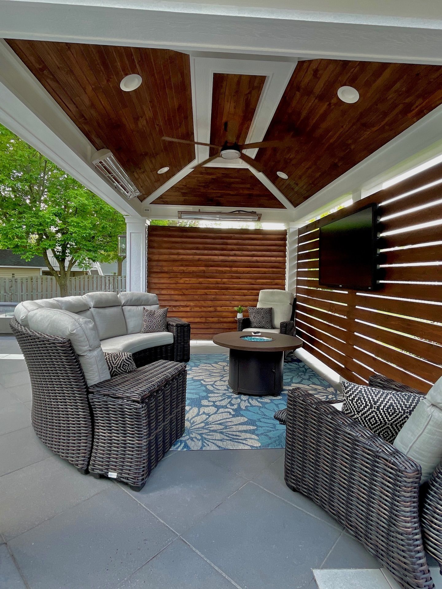 Outdoor living space with wicker furniture, a wood ceiling, and a TV.