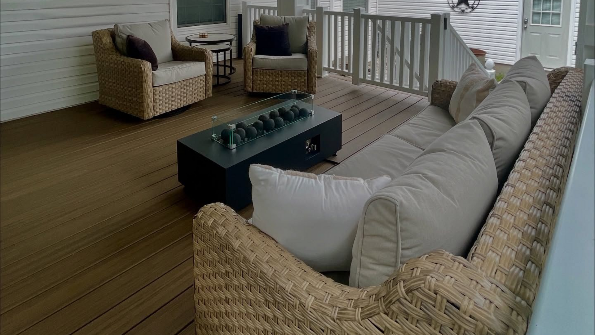 Covered outdoor patio with wicker furniture, wood ceiling, and string lights.