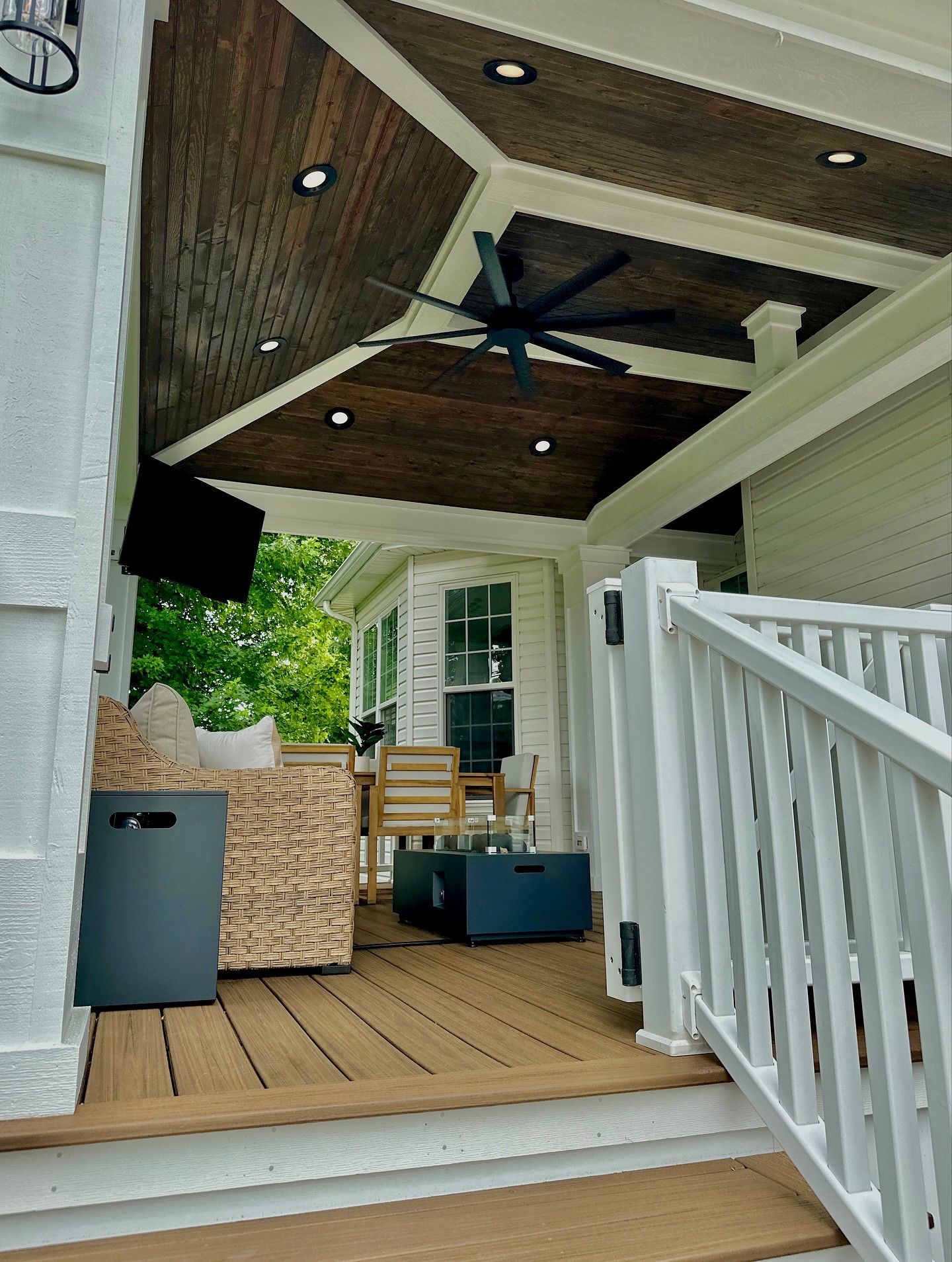 Covered outdoor porch with wood ceiling, dark fan, built-in lights, and white trim.