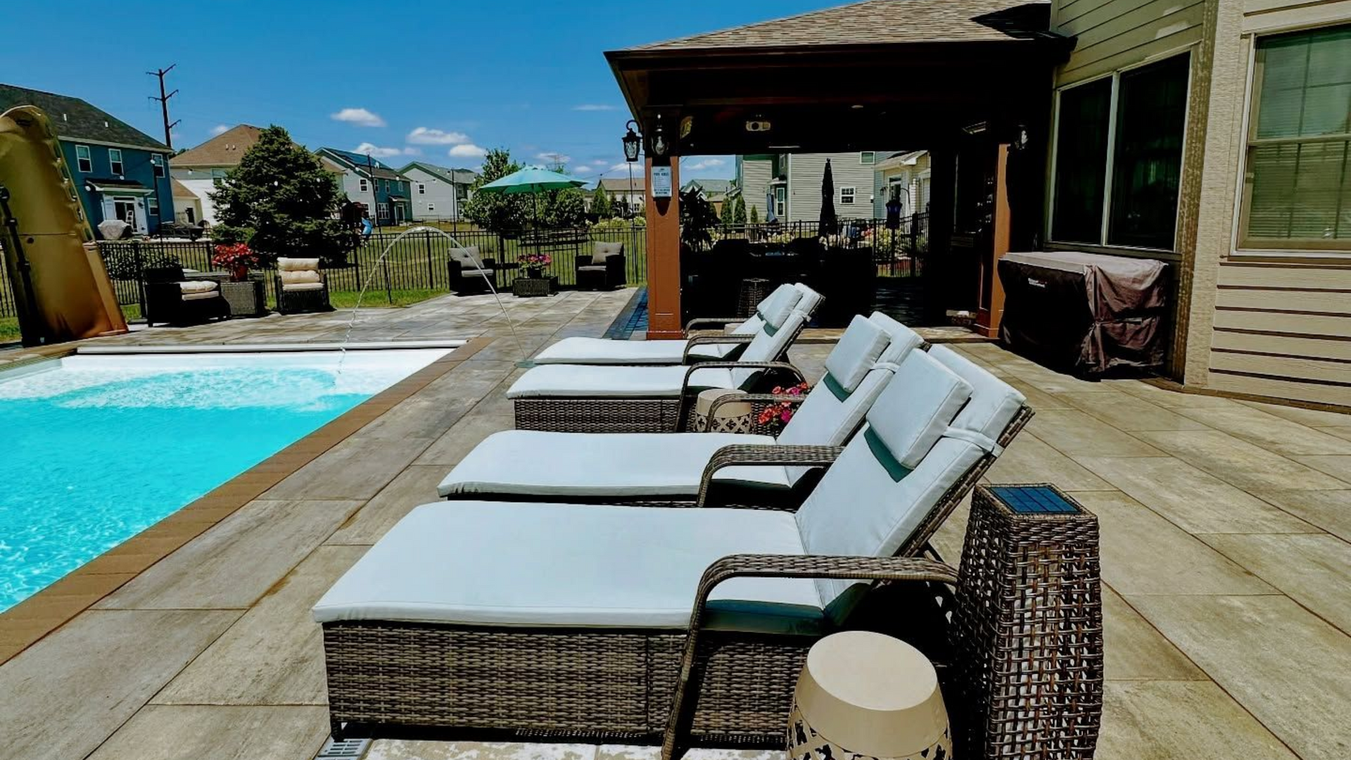 Lounge chairs by a pool with a cabana in the background on a sunny day.