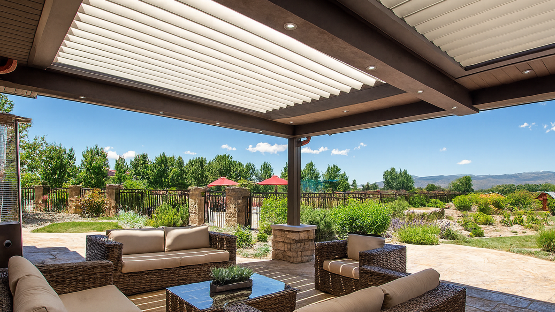 Patio with couches, overhead latticework, and scenic outdoor view.