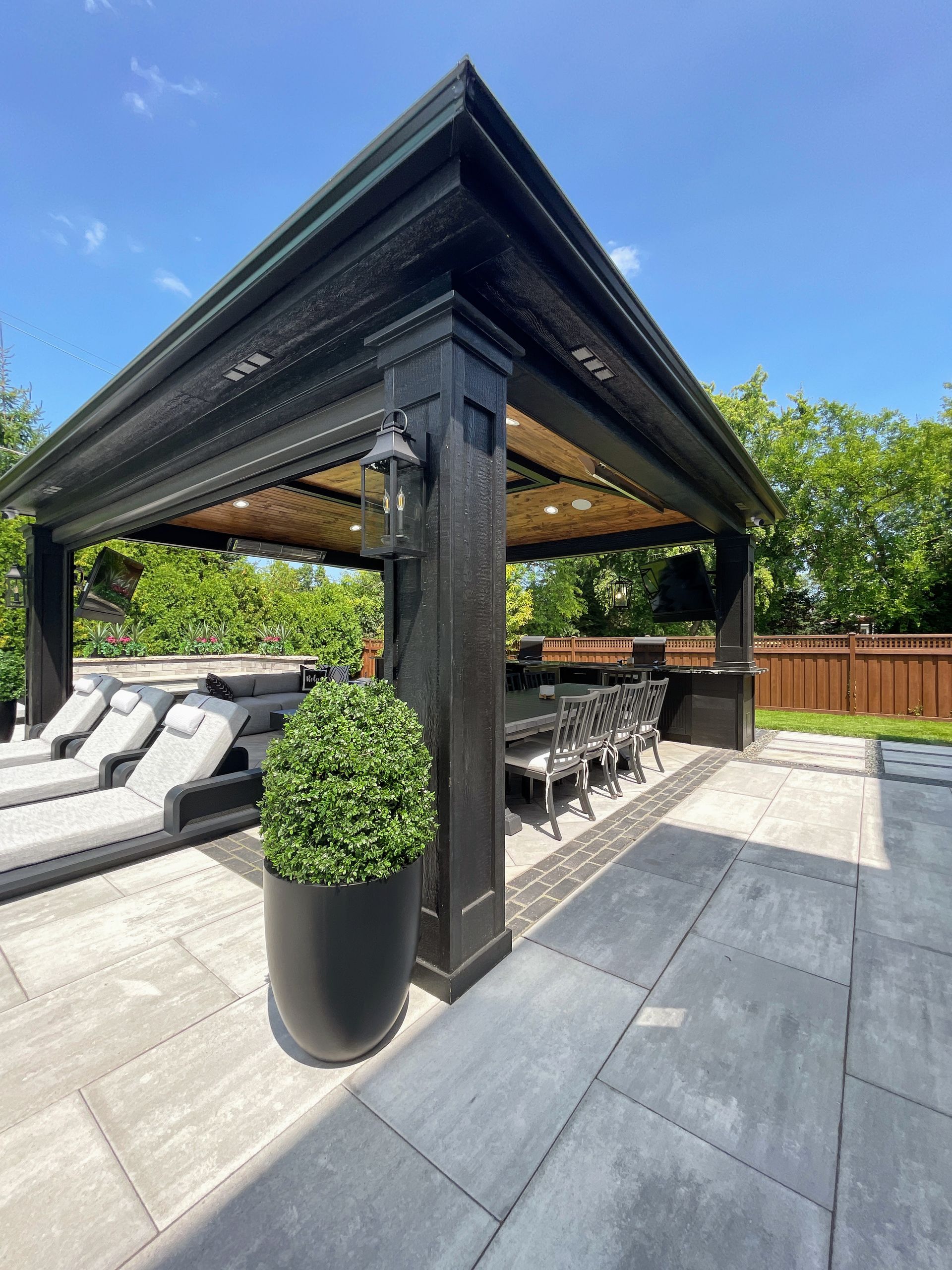 White covered patio with stairs, railing, and string lights. Green lawn surrounds.