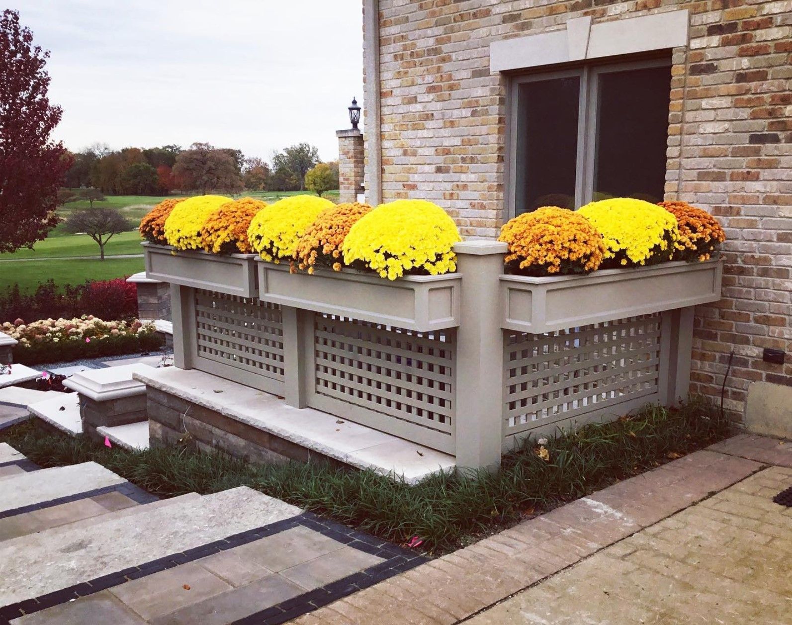 Stone building with flower boxes filled with yellow and orange mums.