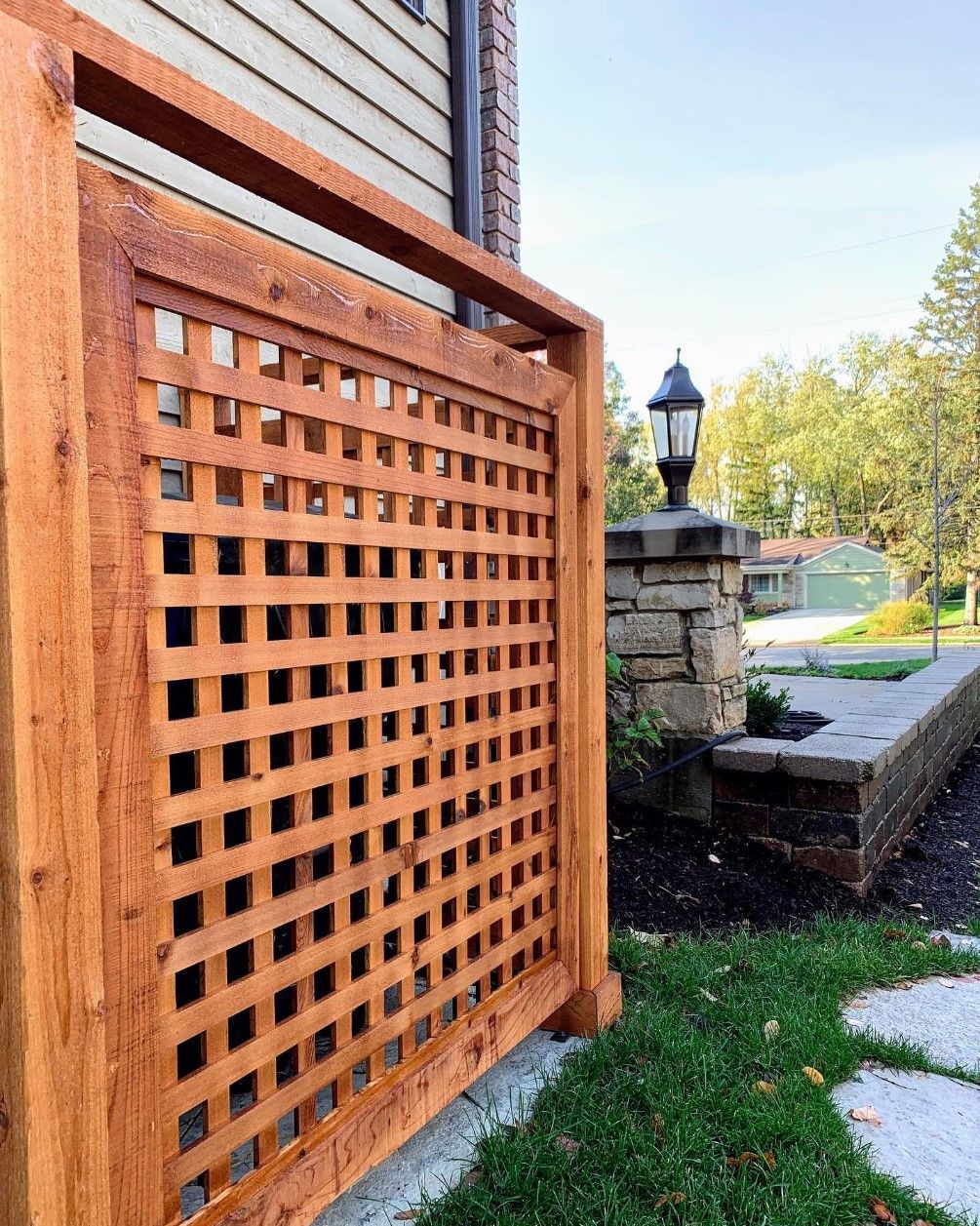 Wooden lattice privacy screen near a brick structure.