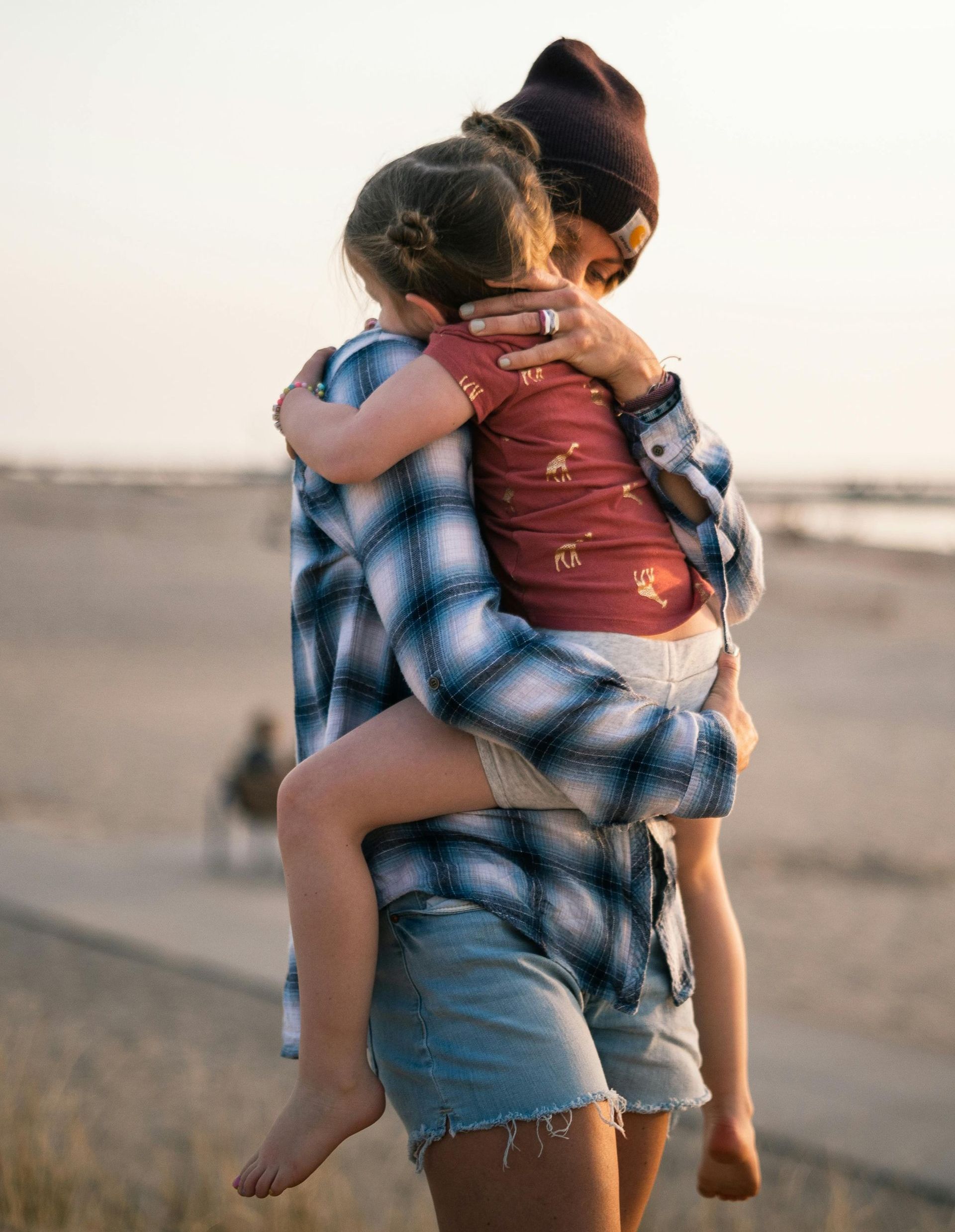 A woman is holding a little girl in her arms on the beach.