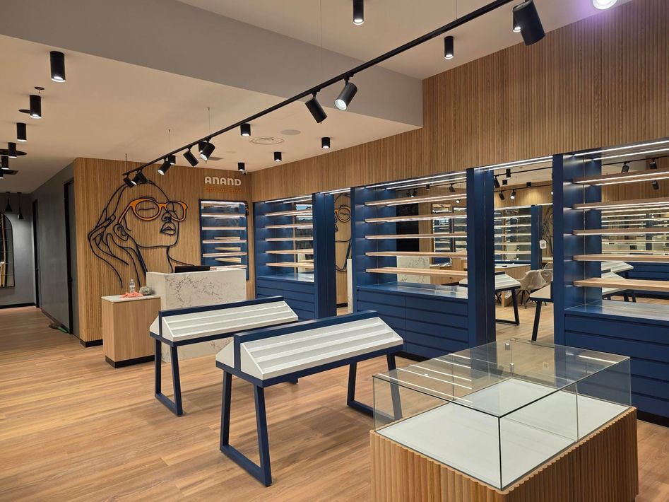 Empty modern retail store interior with wooden floors, blue wall shelving, and display tables.