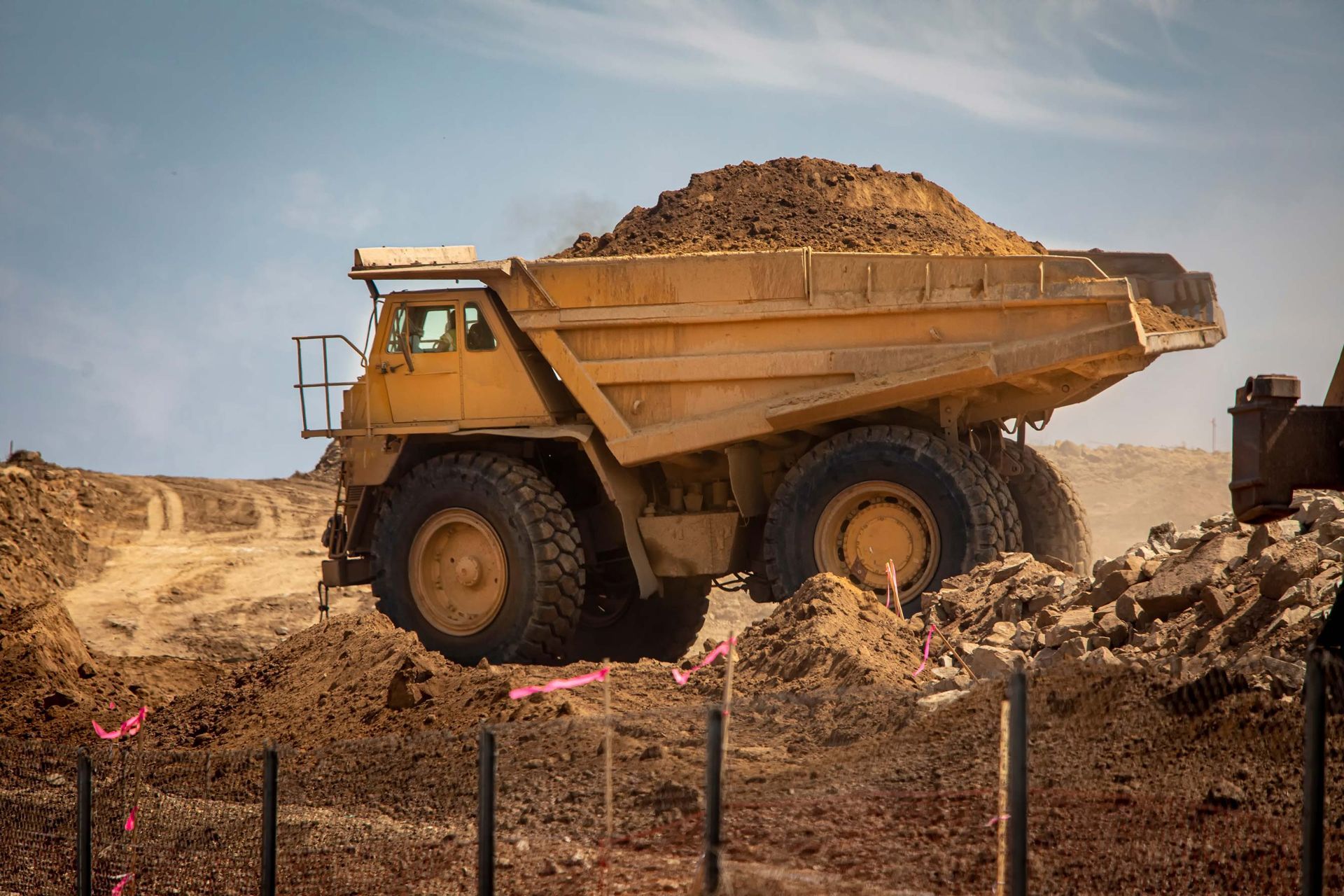 Large yellow dump truck carrying dirt on a construction site.