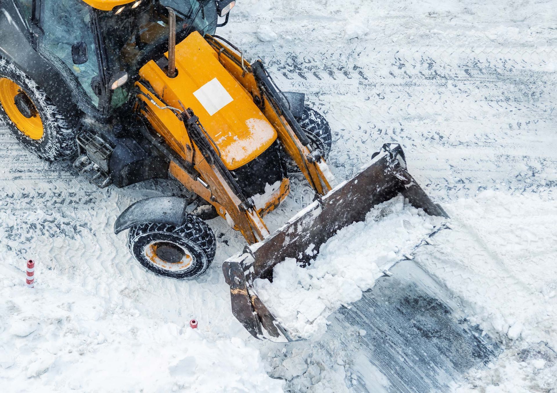 Yellow snowplow clearing snow from a road.