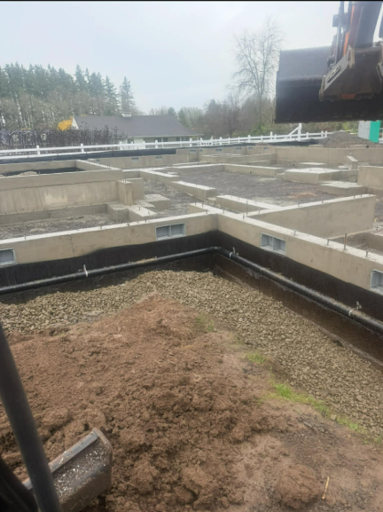 Yellow bulldozer pushing earth on a construction site; blue sky in the background.