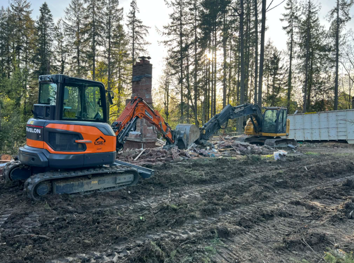 Yellow excavator on a dirt ground with a blue sky background.