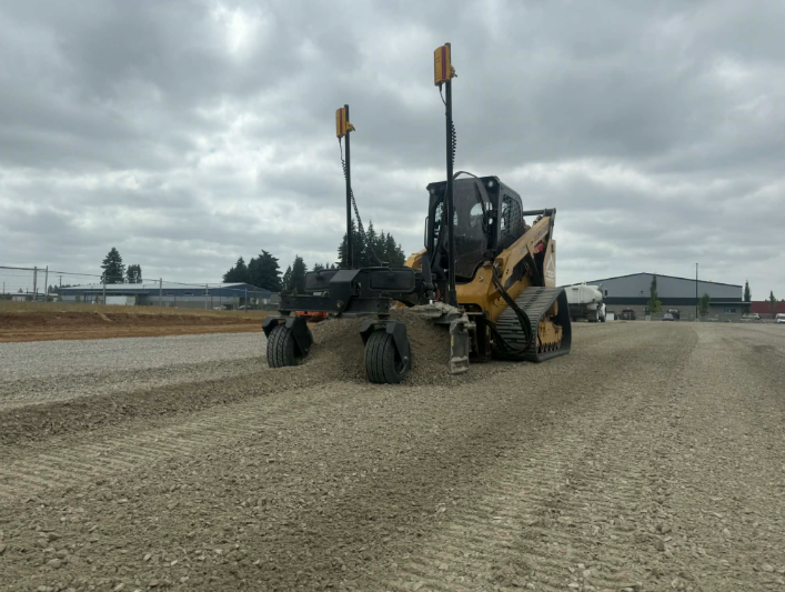 Bulldozer pushing red dirt at a construction site, blue pipes nearby, trees in the background.