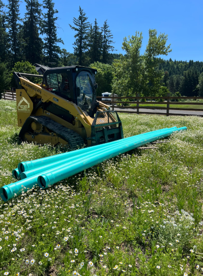 Yellow excavator digging into a pile of dirt under a blue sky.