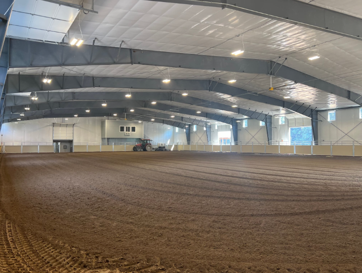 Yellow excavator scoops earth at a construction site against a sunset sky.