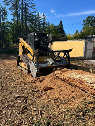 Yellow loader moving dirt in a field on a cloudy day.