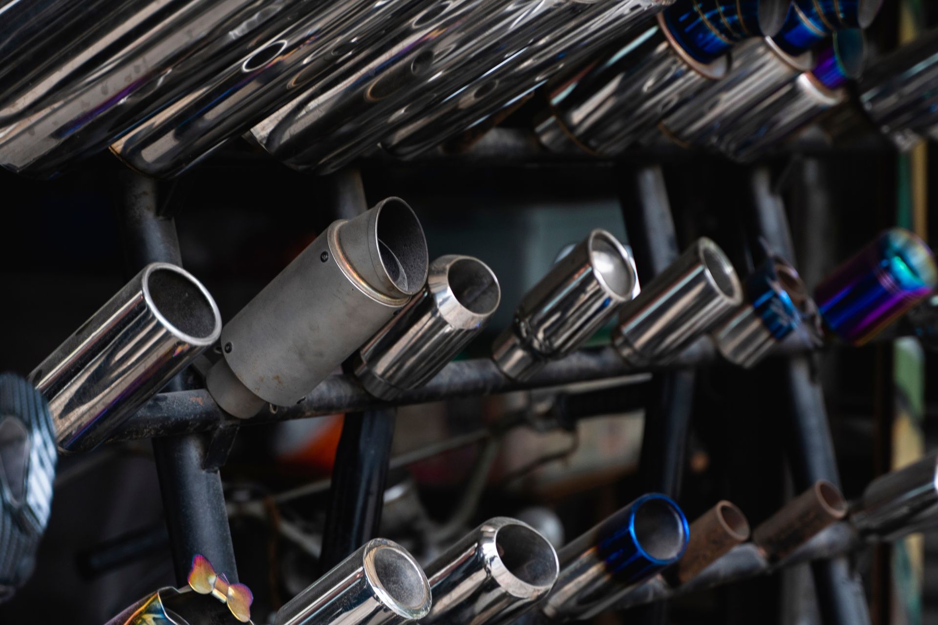 Multiple shiny metal exhaust pipes arranged on a rack.