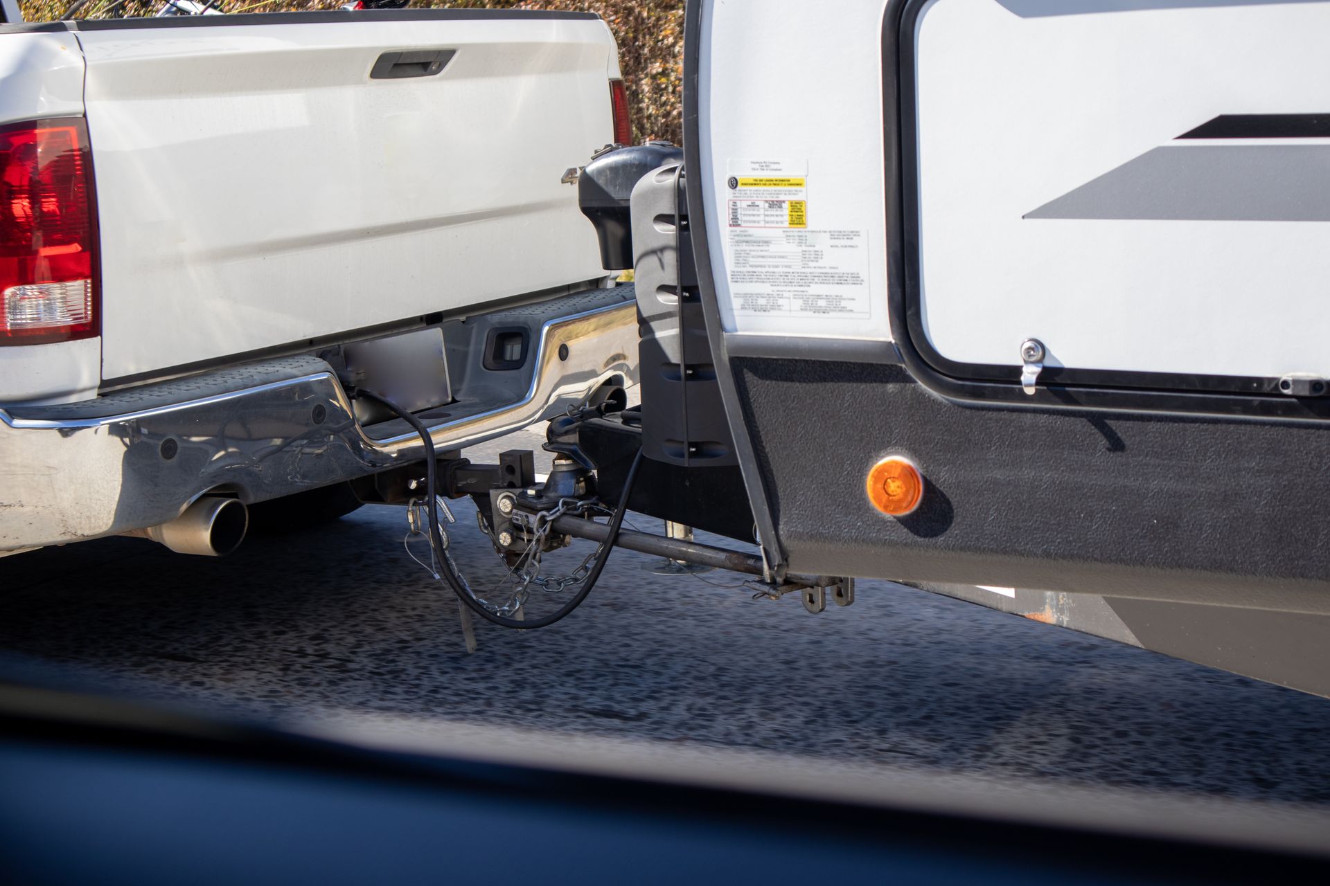 Pickup truck towing a trailer with a secured hitch connection and safety chains attached. Pickup truck towing a trailer with a secured hitch connection and safety chains attached.