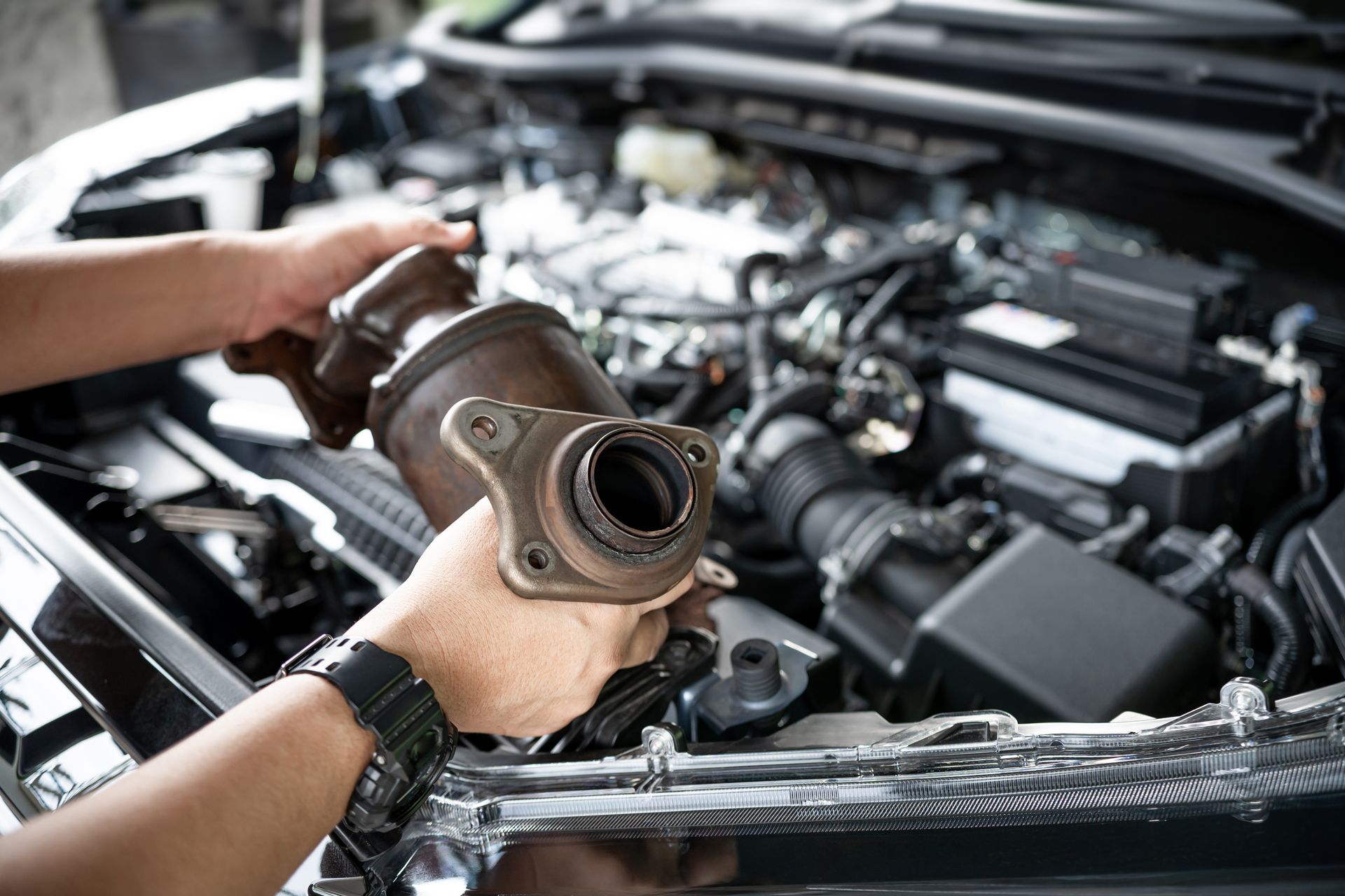 Mechanic holding a removed catalytic converter during an exhaust system inspection Mechanic holding a removed catalytic converter during an exhaust system inspection
