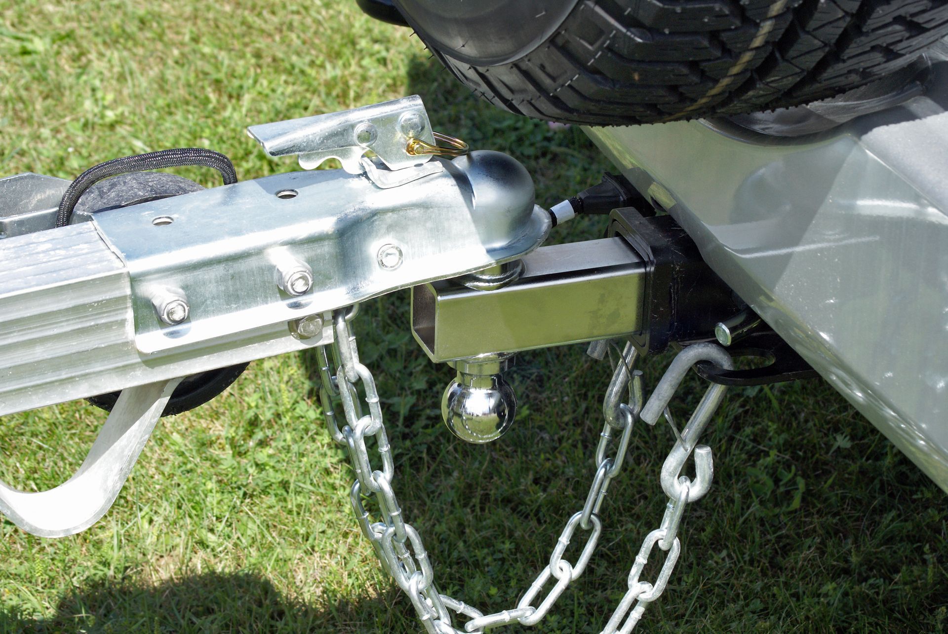 Close-up of a trailer hitch securely connected to a vehicle with chains and wiring.