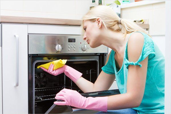 Home Cleaning — Pretty Girl Cleaning the Oven in Scottsdale, AZ